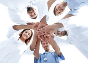 Foto dal basso di un gruppo di medici che uniscono le loro mani in segno di collaborazione