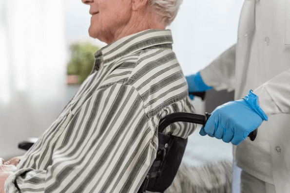 Un anziano in sedie a rotelle che viene trasportato da un medico