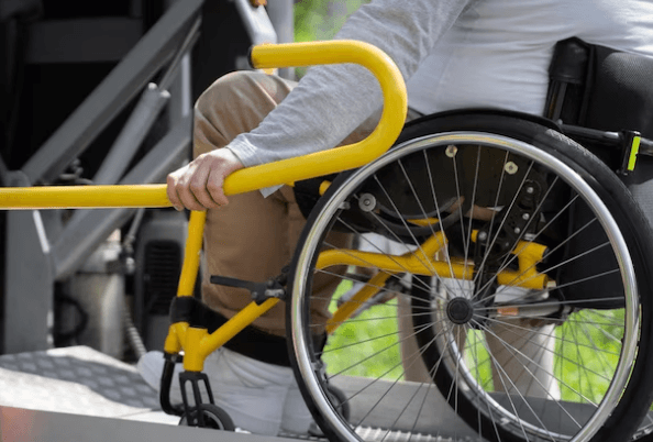 Un disabile su sedia a rotelle mentre sale sull'ambulanza grazie all'ausilio della pedana e del bracciolo
