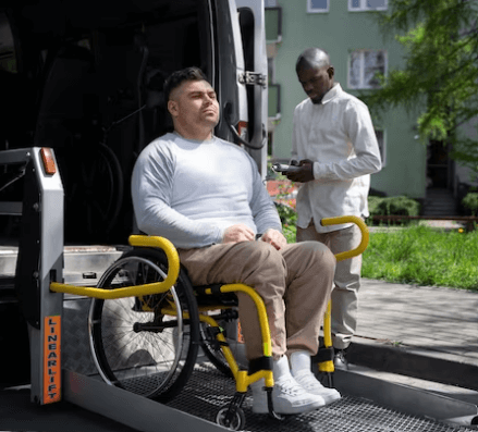 Un disabile in carrozzina mentre sale in ambulanza con apposita pedana controllata dall'assistente
